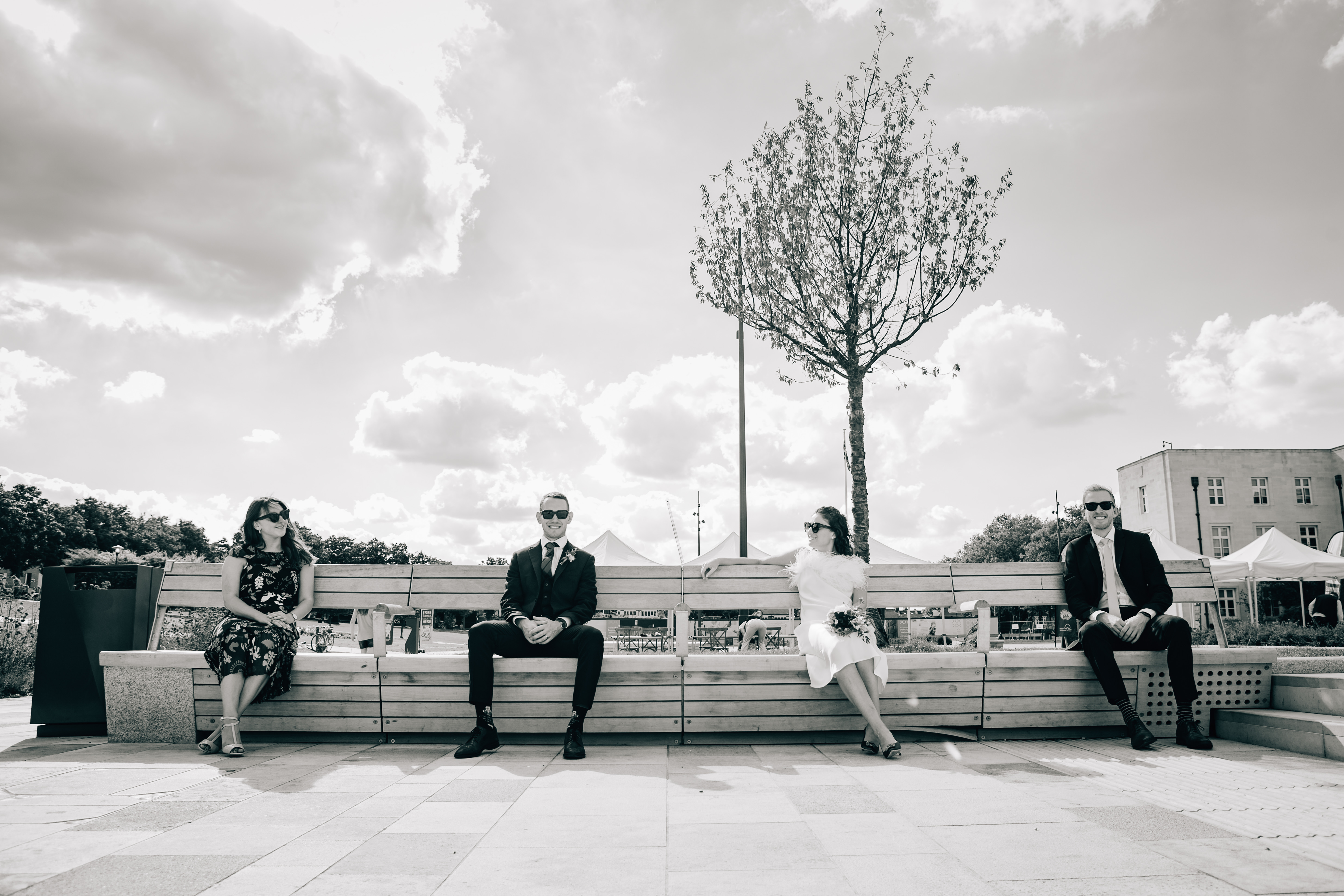 image of four people in a wedding party sitting on benches 